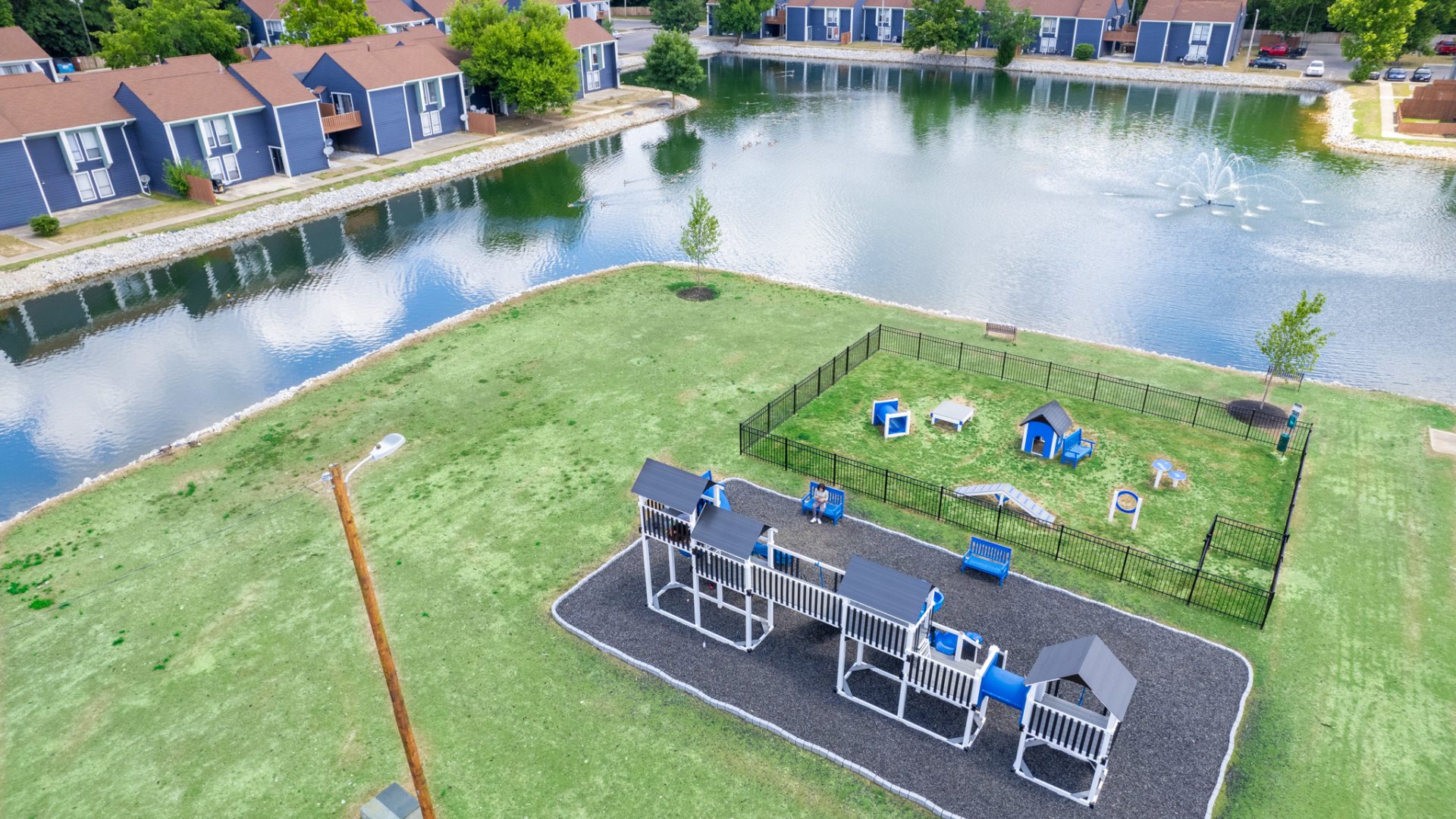 an aerial view of a park with a lake and a playground at The Lakeshore Cove