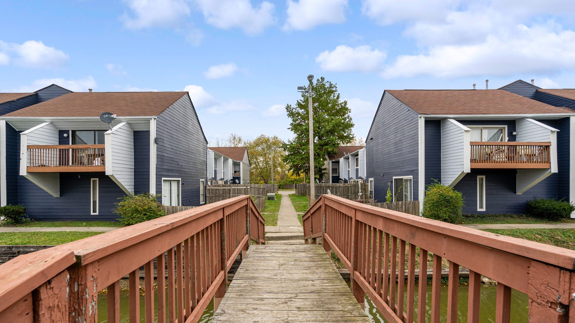 a wooden walkway leads to two apartment buildings at The Lakeshore Cove